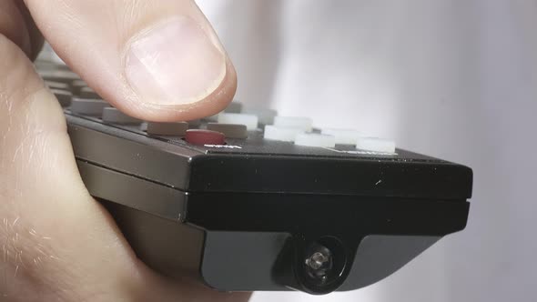 Front View of a Caucasian Male Hand Holding the TV Remote Control and Turning Smart Tv on or Off