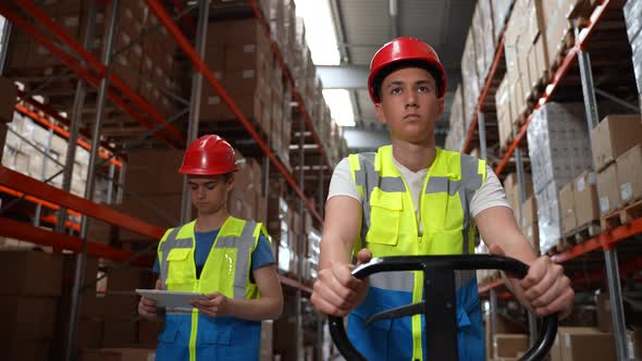 Young Warehouse Workers Walking Along Aisle