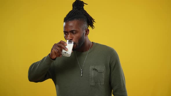 Handsome African American Man Drinking White Milk with Satisfied Facial Expression Looking at Camera