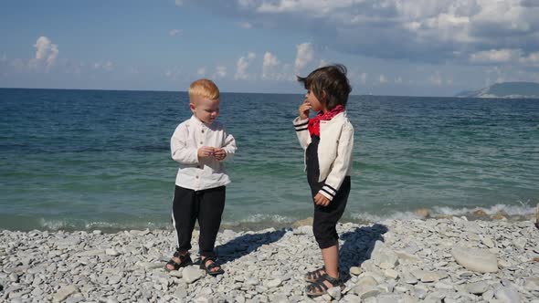 Two Boys Children in Fashionable Clothes Walk on the Stone Sea Beach