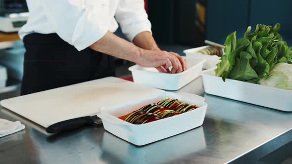 Close-up: The chef is serving ratatouille in a bowl. The process of preparing food in a restaurant.