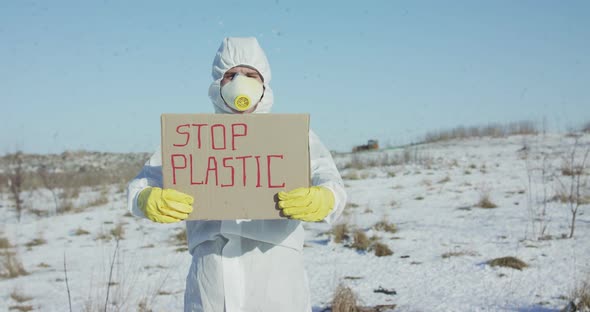 Man Wore in Protective Suit Show Stop Plastic Sign on Abandoned Nature in Winter