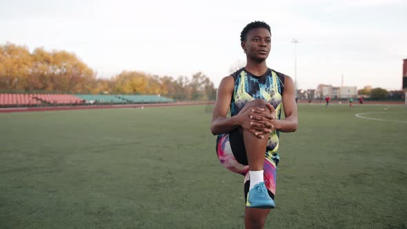 Young African American Woman Training on Soccer Field and Doing Static Exercises Stretching While