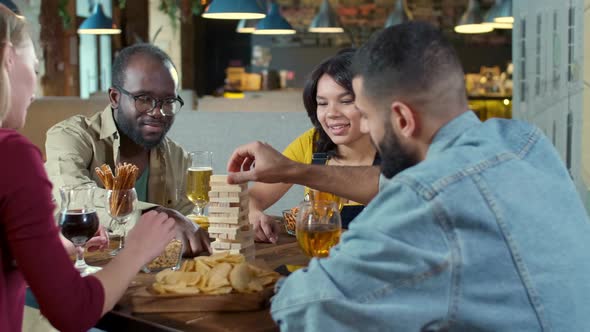 Four friends playing Jenga in bar