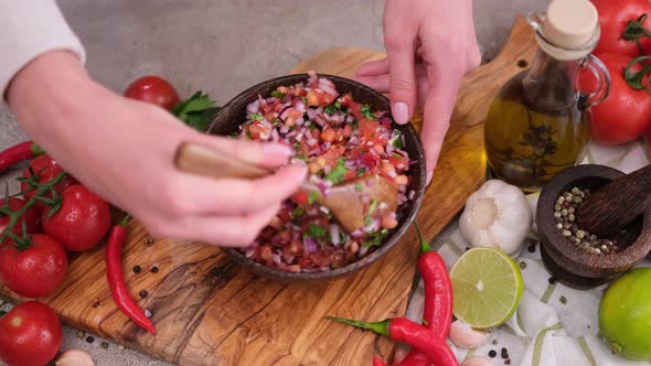 Slow Motion Shot of Woman Mixing Salsa Dip Sauce Ingredients in Wooden Bowl