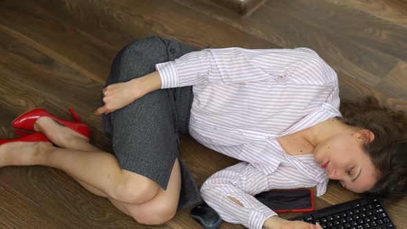 Tired Young Female Office Manager is Lying on the Floor with Keyboard Mouse and Smartphone Lay Flat