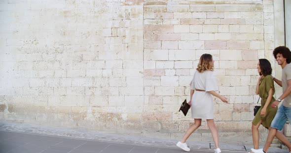 Three People Walking, Smiling and Having Fun Near a Brick Wall in Rural Town of Spello.Group of