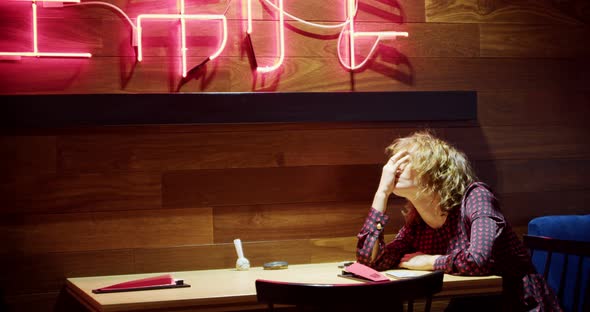 a Sad Young Woman in a Dress is Sitting in an Asian Cafe Waiting for a Boyfriend