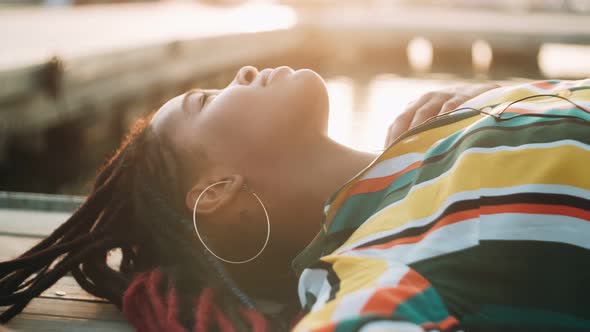 Beautiful African American Girl Listens to Music While Lying on the Beach on a Sunny Day