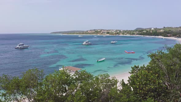 Pleasure boats bobbing in exotic Caribbean off stunning beach; aerial