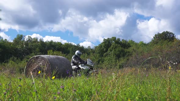 MOTOR RIDER ARRIVES TO A GRASS FIELD IN NATURE ENVIRONMENT, COUNTRYSIDE