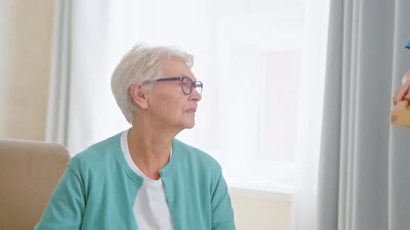 Employee carries tray with lunch and cheers up sad mature woman patient