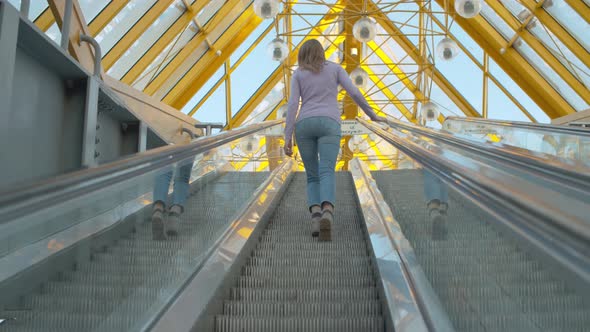 Young Woman Climbing Up the Escalator