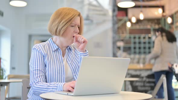 Creative Old Woman Using Laptop Coughing in Cafe