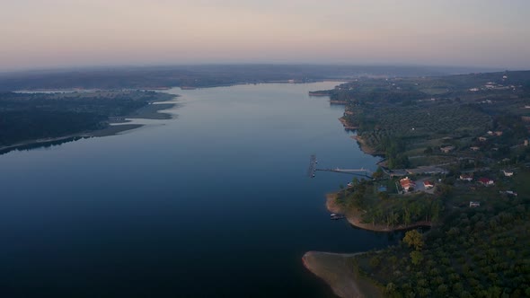 Drone aerial panorama of a desert like hill landscape over lake at sunset in Alentejo, Portugal