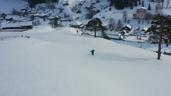 Aerial View of a Snowboard Going Uphill Near the Village at Sunset