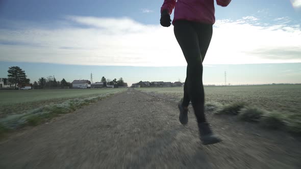 Feet of Woman Running on Dirt Track in Autumn Front View