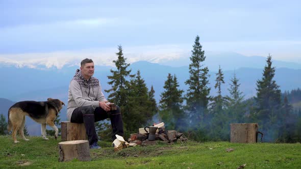 Man with Dog Near a Fire in the Mountains