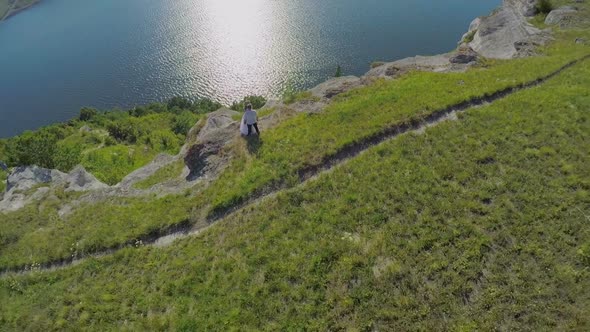 Aerial Photography of the Bride and Groom on a Beautiful Steep Bank Near a Wide River