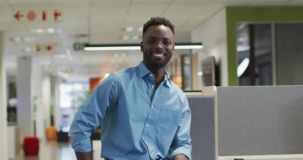 Video of happy african american businessman looking at camera in office