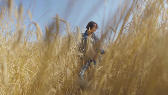 Portrait Adorable Young Woman with Short Hair in Jeans Jacket Standing on the Wheat Field at Sunrise