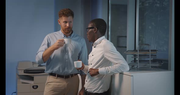 Interracial Business Colleagues Drinking Coffee While Talking in Office