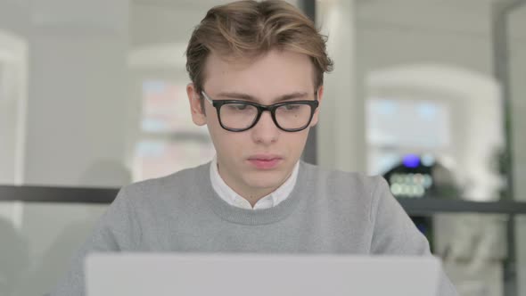 Close Up of Young Man Shaking Head As No Sign While Using Laptop