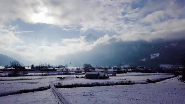 A car and a train are driving to the right in a beautiful winter scenery in Switzerland.