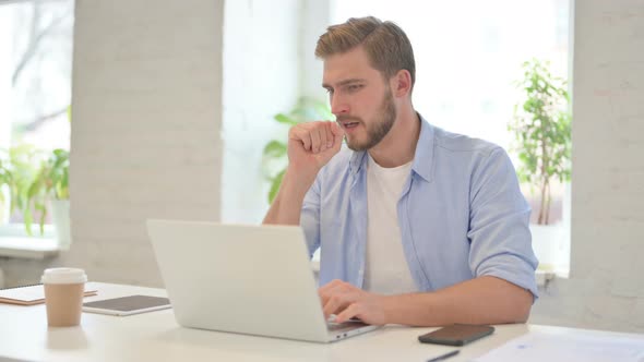 Young Creative Man with Laptop Having Coughing in Modern Office