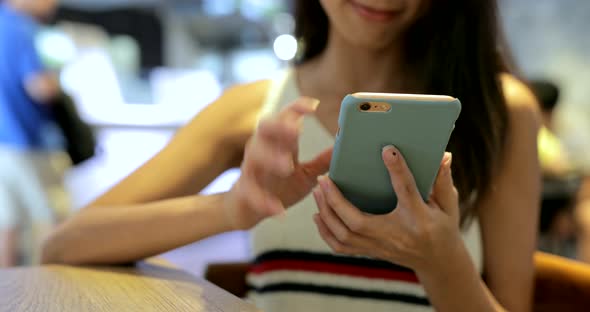 Woman typing on cellphone in restaurant 