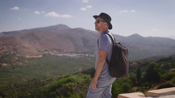 Happy Tourist with a Backpack Enjoying a Beautiful View of the Valley and Mountains