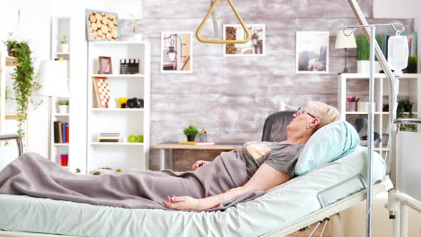 Retired Disabled Lady Lying in Hospital Bed in Cozy and Bright Room in Retirement Home