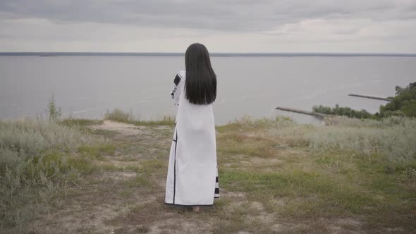 Rear View at Adorable African American Woman Wearing Long Summer Fashion Dress Walking on the Field