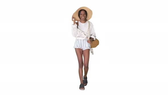 Relaxed African American Girl Walking Wearing a Straw Hat and a Bag on White Background