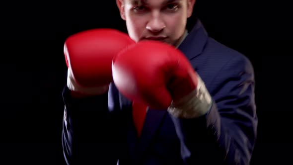 a Young Man of Caucasian Appearance in a Suit Raises His Hands with Boxing Gloves and Begins