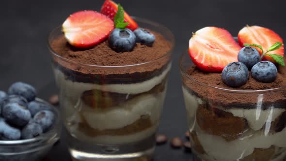 Classic Tiramisu Dessert with Blueberries and Strawberries in a Glass on Dark Concrete