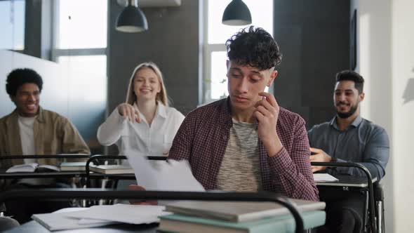 Upset Distressed Hispanic Male Student Sitting at Desk in Classroom Alone Feels Disappointment