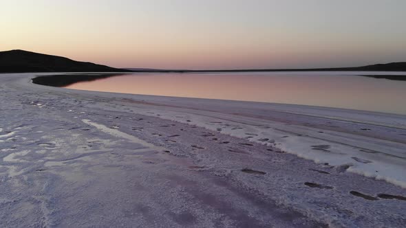 Aerial View of Flying Over the Salty Shore of Pink Salt Lake in the Evening at Dusk Blue Sky