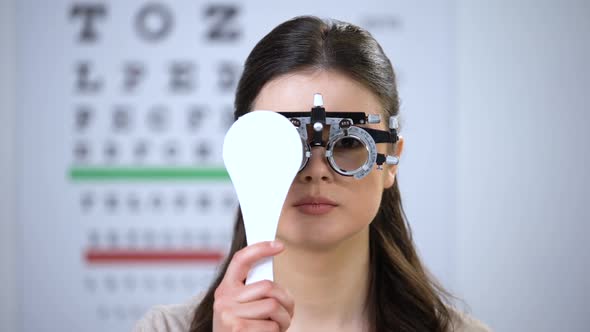 Woman in Phoropter Closing One Eye and Smiling, Choosing Correct Lens Diopter