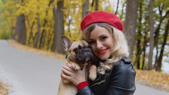 Portrait of a Smiling Happy Cheerful Woman with Funny French Bulldog in Autumn Park