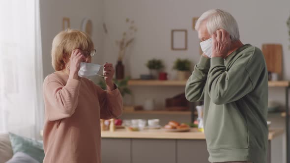 Senior Couple Putting On Protective Masks at Home