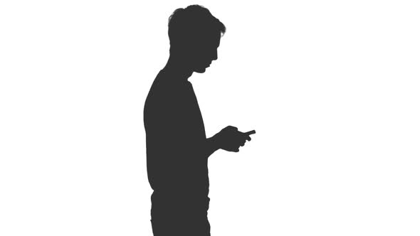 Silhouette of Young Man Walking and Typing Sms alt