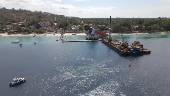 Aerial circling shot of platform ferry loading cargo freight at pier of GIli Trawangan,Indonesia.