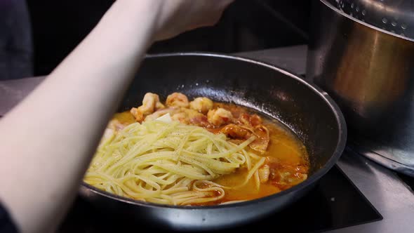 The Chef Cooks Pasta with Shrimp in a Frying Pan