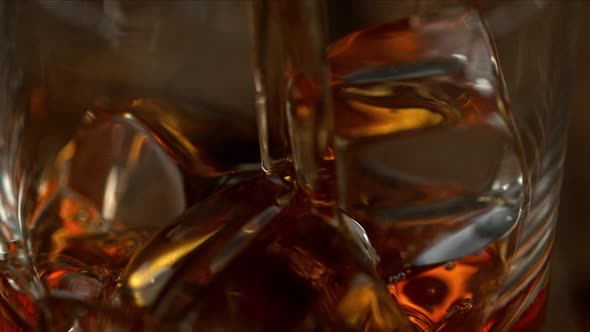 Super Slow Motion Macro Shot of Pouring Whiskey Into Glass with Ice Cubes with Camera Movement