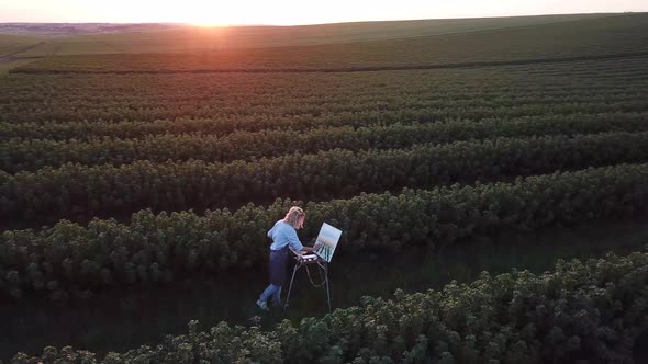 The young artist paints a summer landscape. The girl in the nature of the artist paints