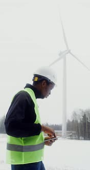 A Man in a Work Uniform is Diagnosing a Wind Turbine Using a Digital Tablet