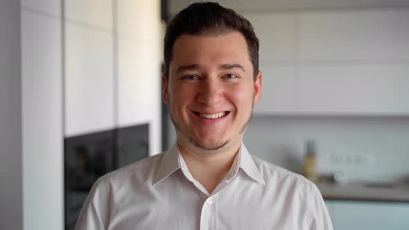 Close up portrait smiling man looking at camera at home. Well dressed man in white shirt