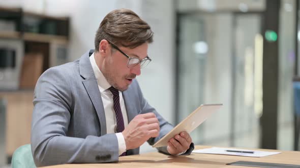 Successful Businessman Celebrating on Tablet in Office