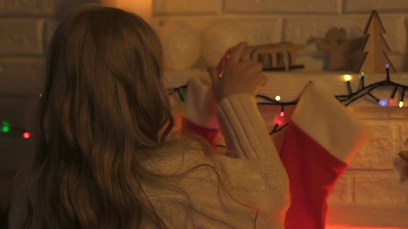 Girl Puts Candies Into Christmas Stockings, Gift for Parents, Festive Decoration